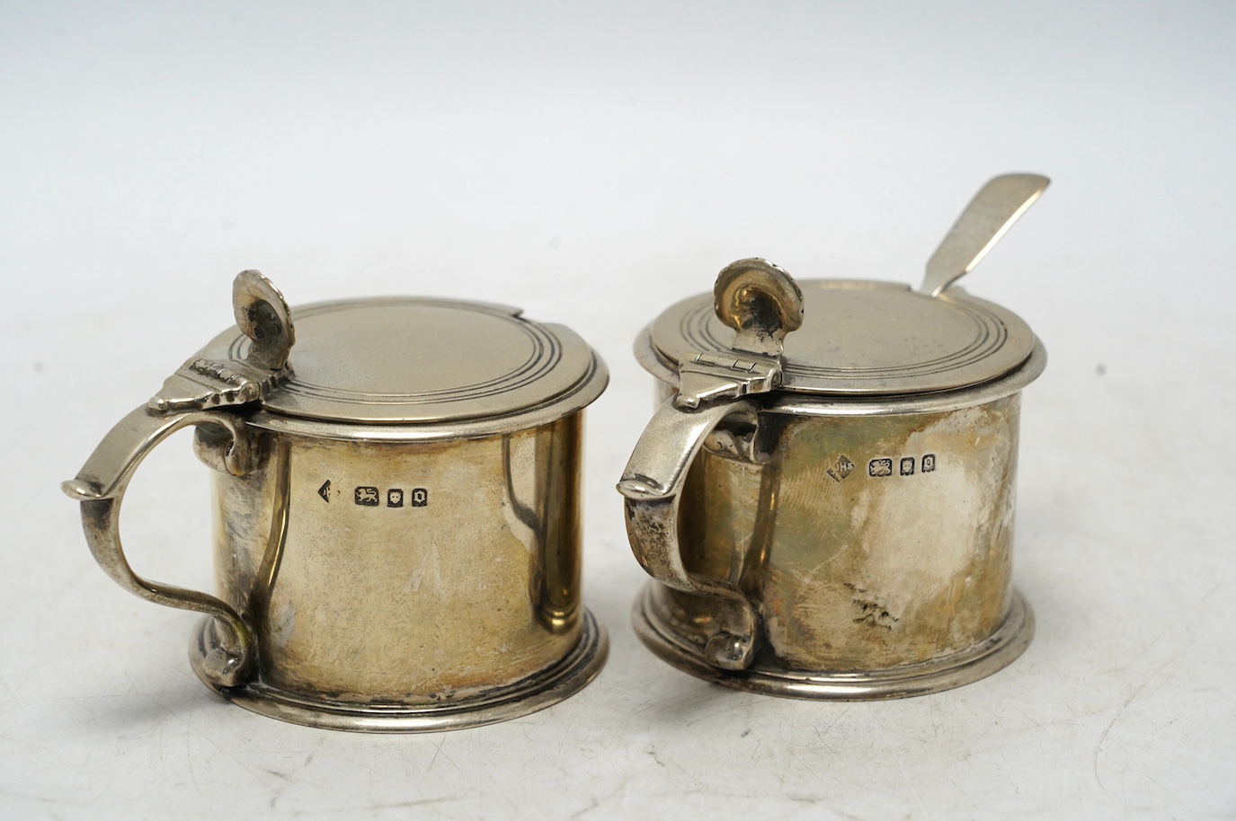 A pair of George V silver drum mustards, by Harman & Co, London 1929, 70mm, one with associated spoon. Condition - fair